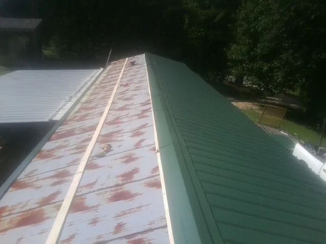 Old rusted panels beside newly installed green metal roofing — Wind Damage Roof Repair by Roofing Brothers in Mount Clemens