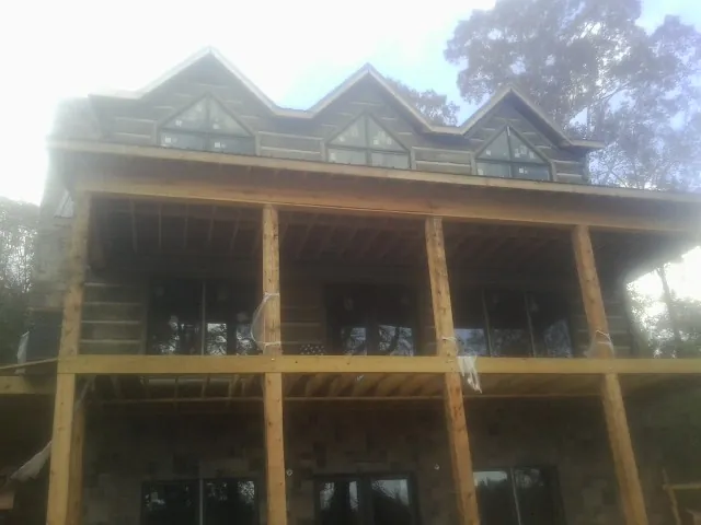 Dormers and porch framing on a large log home under construction — Roof Coating work by our crew in Mount Clemens