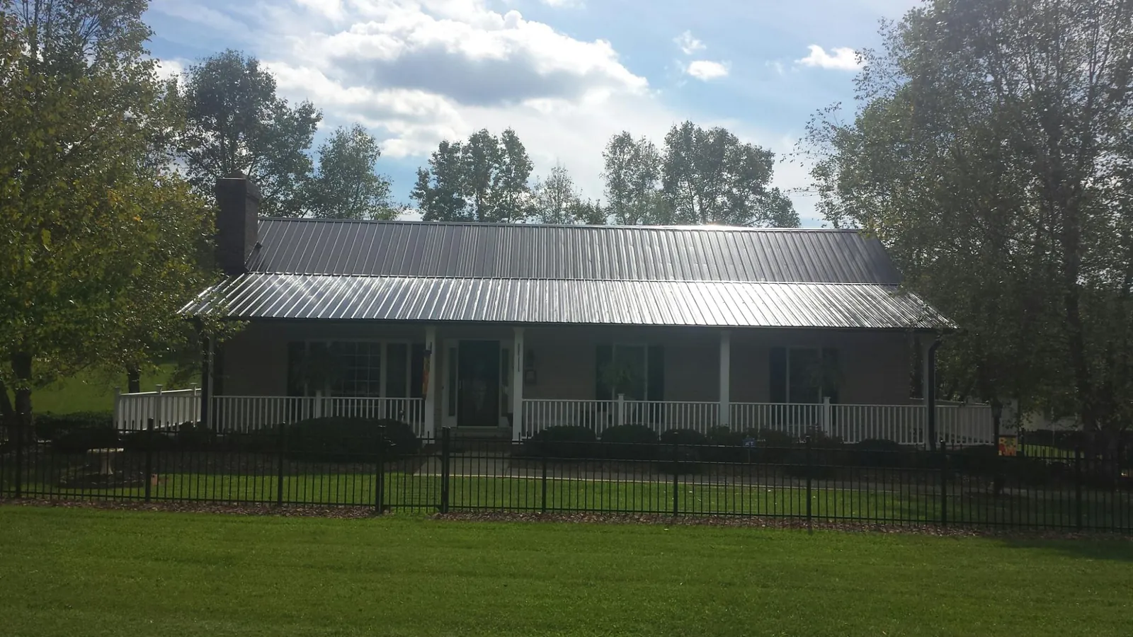 Gray metal roof on a brick ranch with a full width front porch — Gutter Guard Installation work by our crew in Mount Clemens