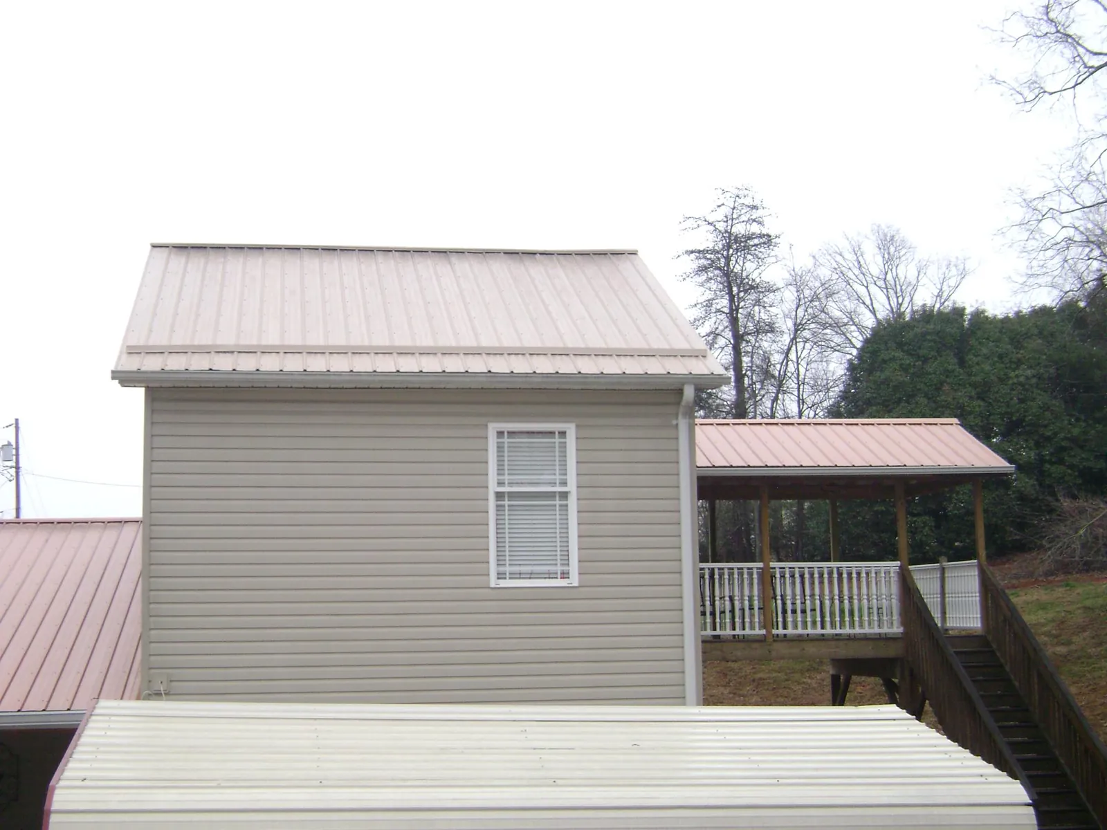 Tan metal roofs on a two story addition and attached porch, from a Roof Replacement job in Mount Clemens