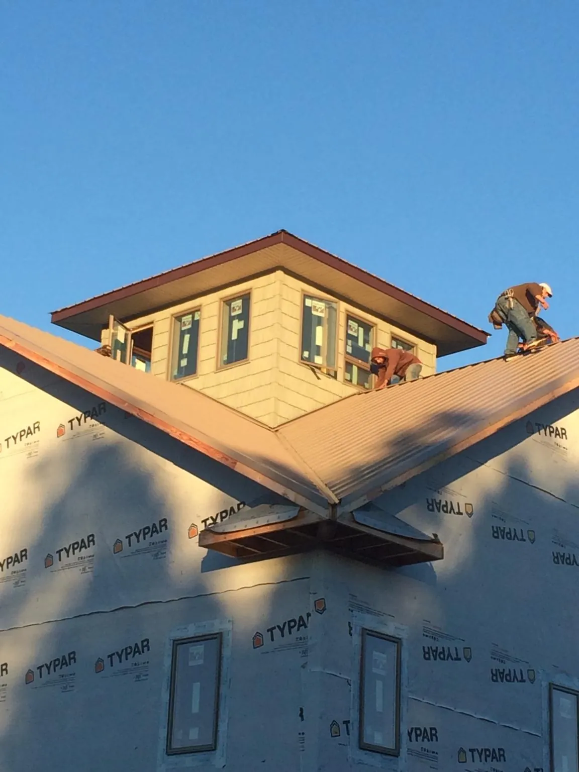 Roofers working around a rooftop cupola on a new metal roof at sunset — Roof Waterproofing in Mount Clemens by Roofing Brothers